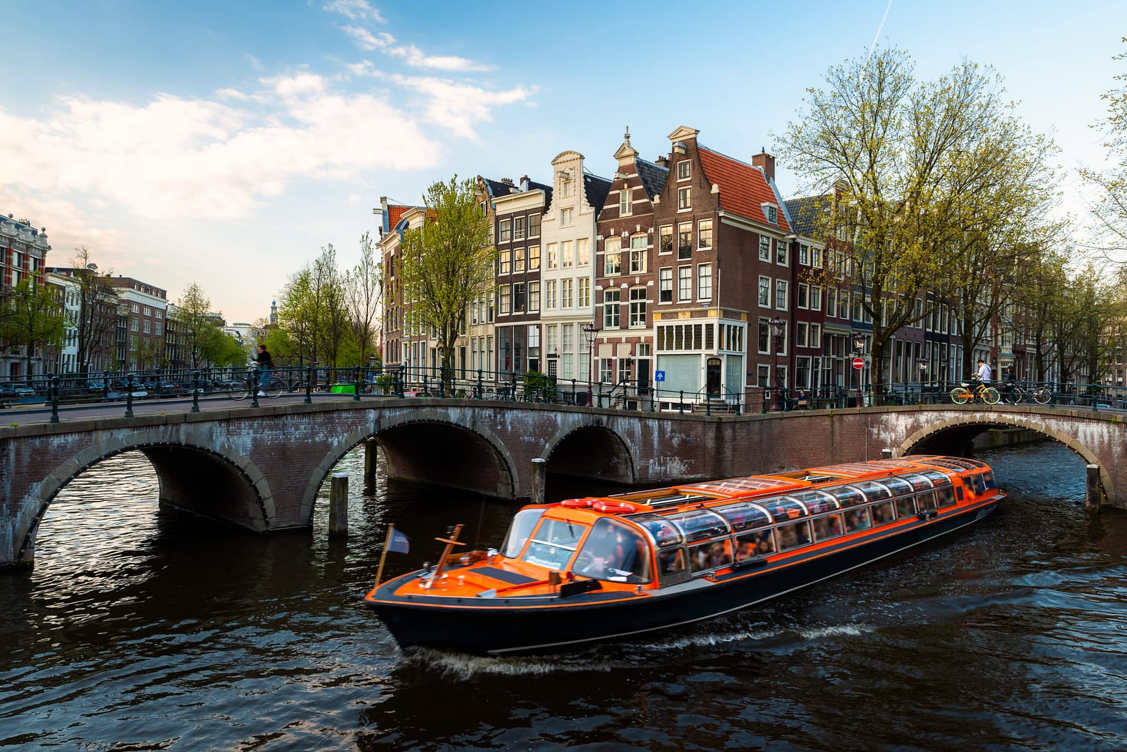 Amsterdam canal cruise ship with Netherlands traditional house in Amsterdam, Netherlands.
