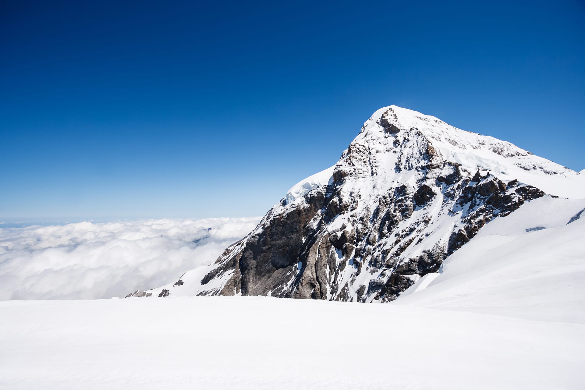 View of Summit of Mount Jungfrau (Jungfraujoch) with cloud and blue sky background, Jungfraujoch Railway Station, Bernese Oberland region, Switzerland, Europe.